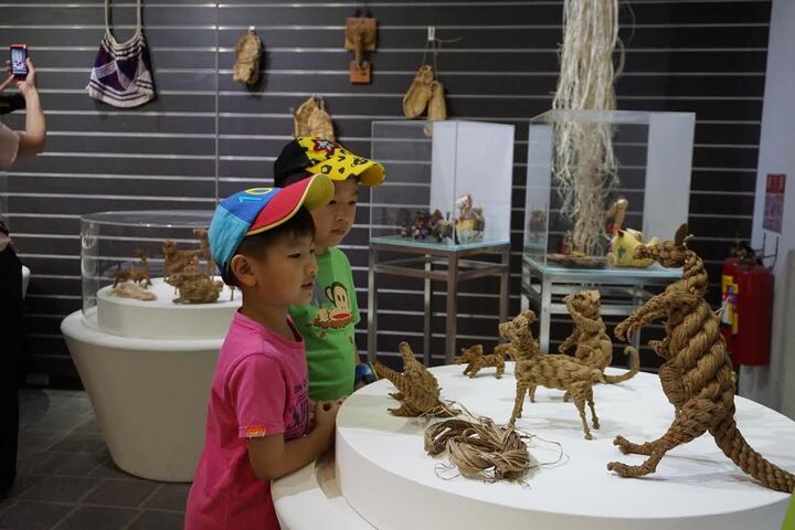 海地無毒教面具高掛植物園溫室 科博館推麻類植物纖維工藝特展-小孩欣賞中