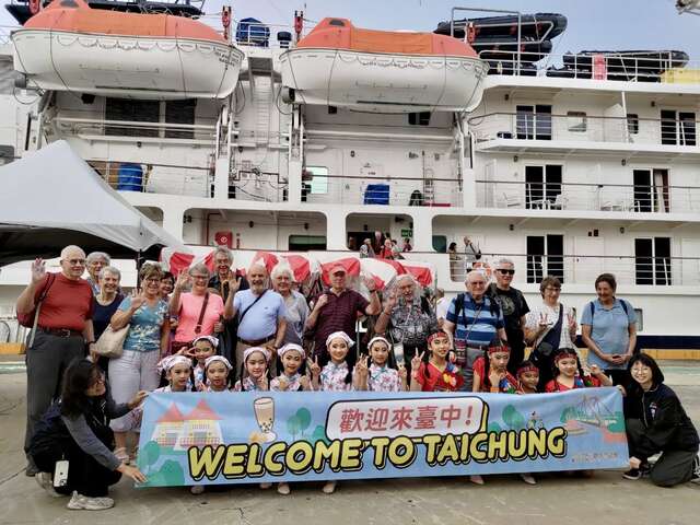 国际游客与本市迎宾表演小朋友合影